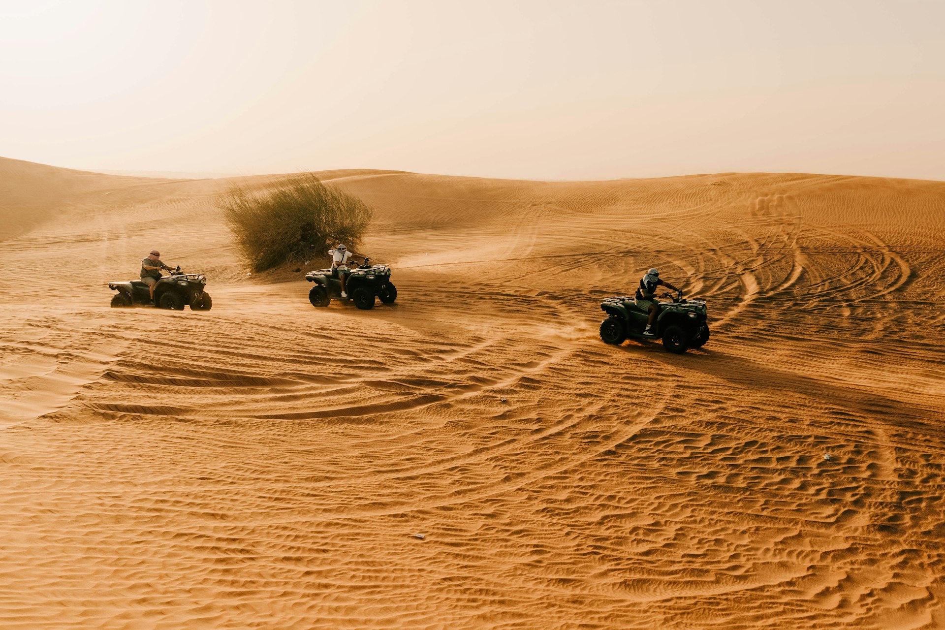 Atvs are riding across the sandy desert.